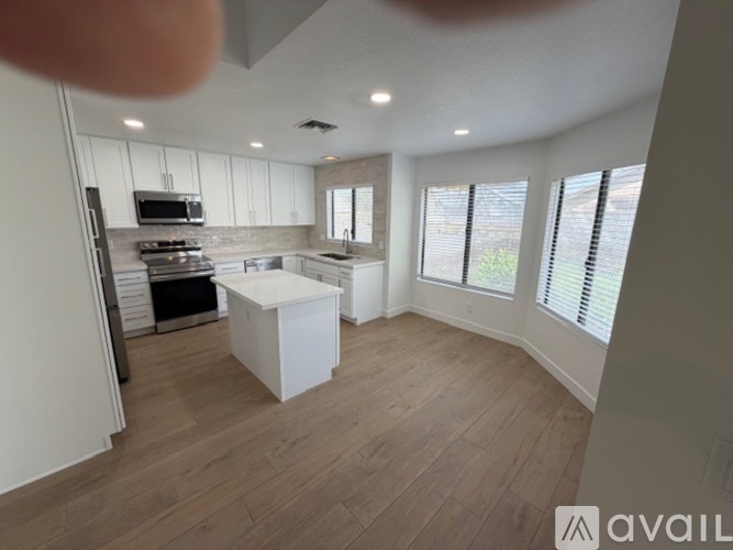 A kitchen with white cabinets and a wooden floor.