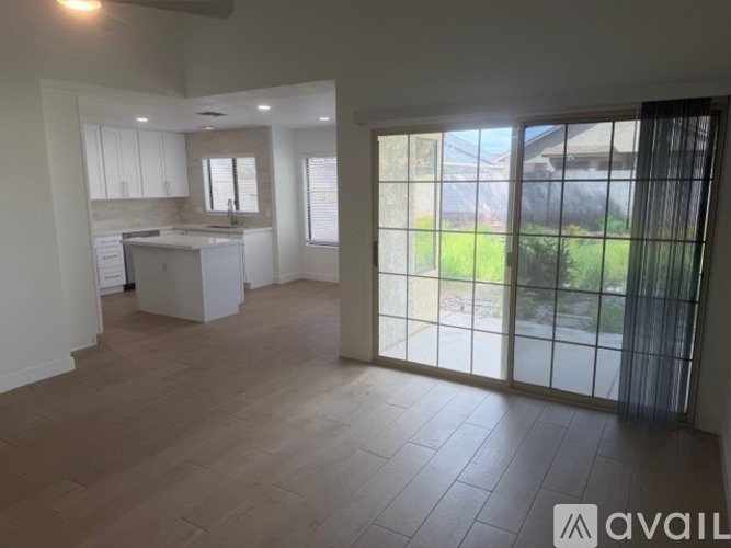 A spacious room with a kitchen area and sliding glass doors leading to a backyard.