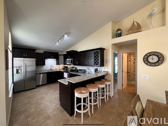 A kitchen with a refrigerator, stove, and bar stools.