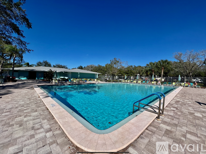 A large swimming pool surrounded by a brick patio and trees.