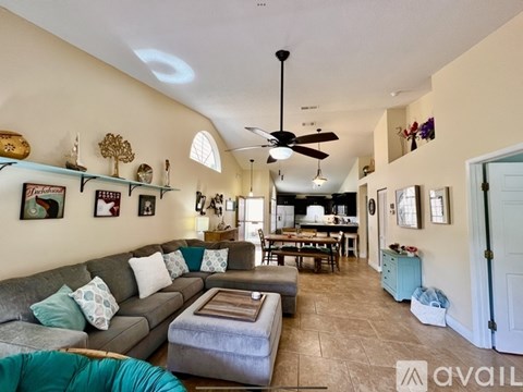 A living room with a grey couch and a ceiling fan.