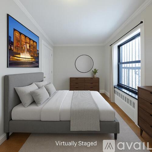 A bedroom with a large bed, a painting on the wall, and a window with blinds.