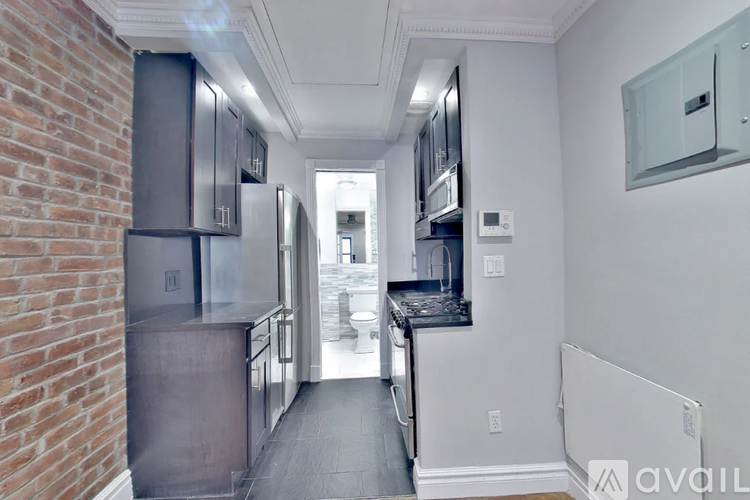 A kitchen with a brick wall and stainless steel appliances.