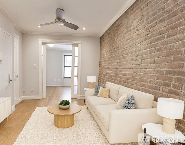 A living room with a white couch, a wooden coffee table, and a brick wall.