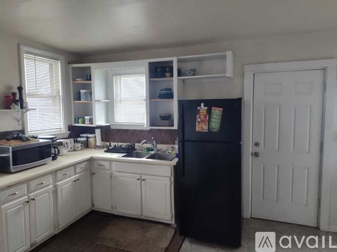 A kitchen with white cabinets and a black fridge.