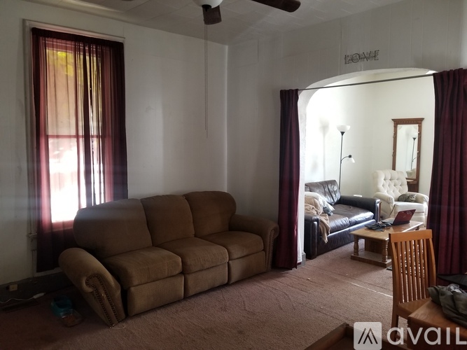 A living room with a brown couch and a fan.