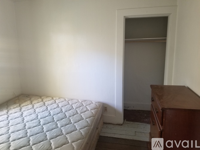 A bedroom with a bed and a wooden dresser.