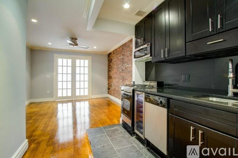 A kitchen with black cabinets and a brick wall.