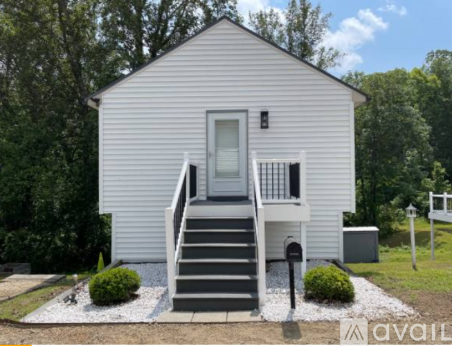 A small white house with a grey front porch and steps.