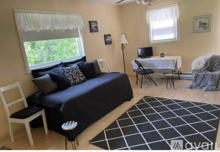 A bedroom with a bed, chair, and a small table.