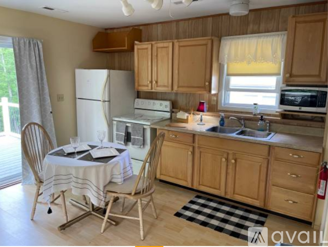 A kitchen with wooden cabinets and a checkered rug on the floor.