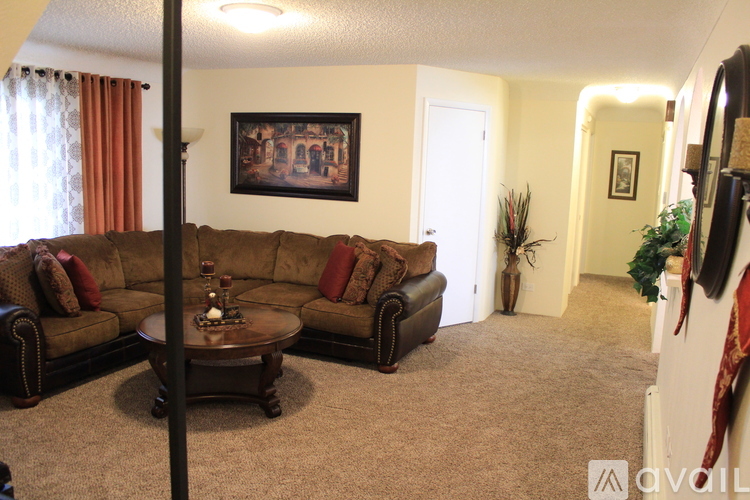 A living room with a brown couch and a painting on the wall.