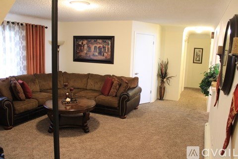A living room with a brown couch and a painting on the wall.