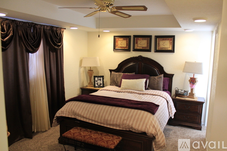 A bedroom with a large bed and a ceiling fan.