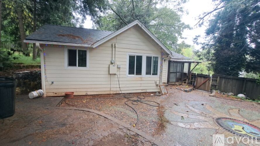 A house with a driveway and a tree in the background.