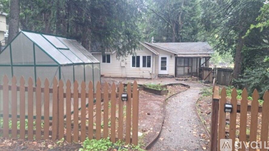 A backyard with a wooden fence and a greenhouse.