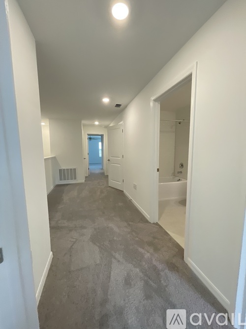 A long hallway with a door on the left and a bathroom on the right.