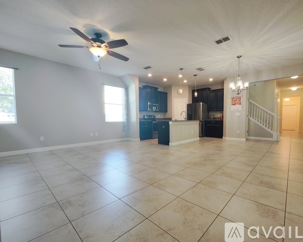 A spacious living room with a ceiling fan and tiled flooring.