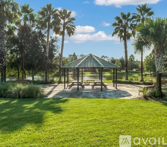 A gazebo is surrounded by palm trees and benches in a park.