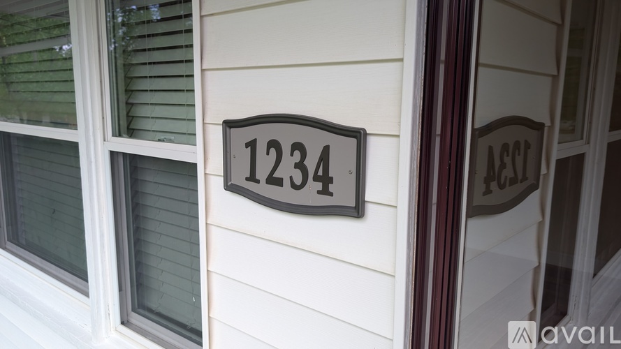 A house number sign reading 1234 is mounted on a white siding wall.