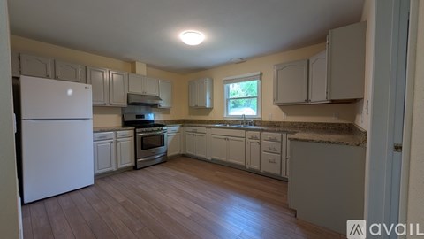 A kitchen with white appliances and wooden floors.