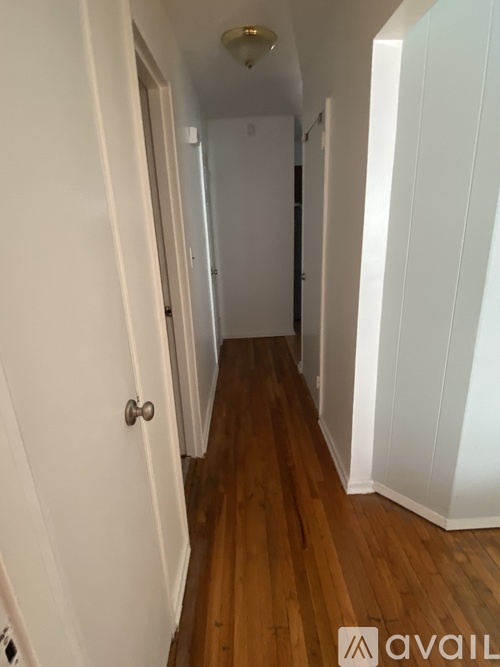 A hallway with wooden floors and white walls.