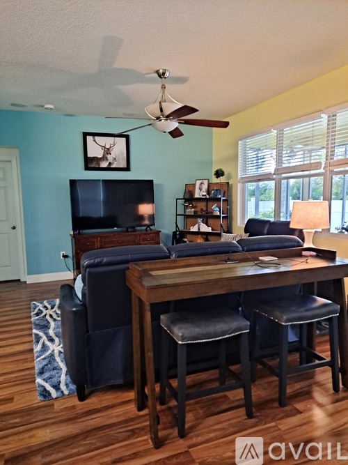 A living room with a television, a couch, a chair, and a table.