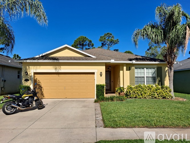 A motorcycle is parked in front of a yellow house.