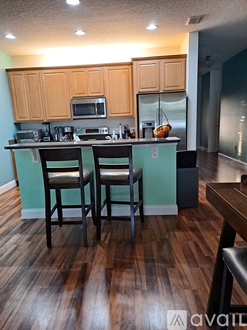 A kitchen with wooden floors and a counter with two chairs.