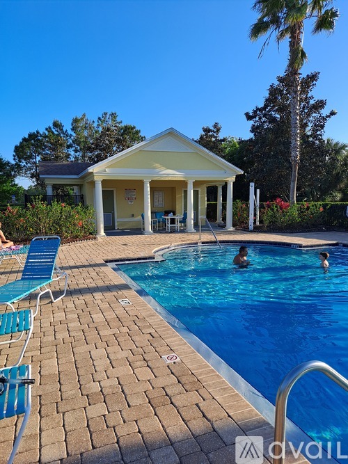 A pool with a house and a palm tree in the background.