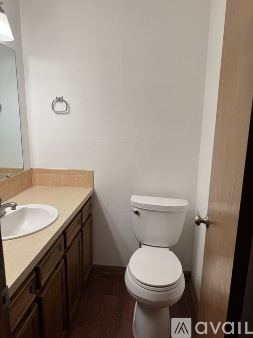 A white toilet in a small bathroom with wooden cabinets.
