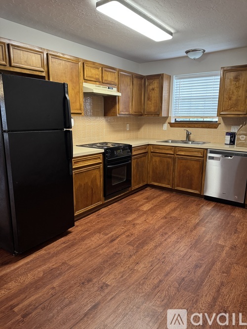A kitchen with wooden cabinets and a black fridge.