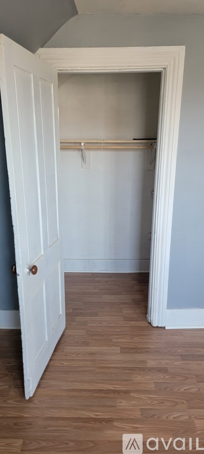A white door is open to a room with a wooden floor.