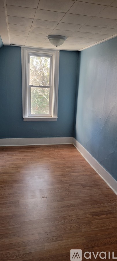 A room with a window and wooden flooring.