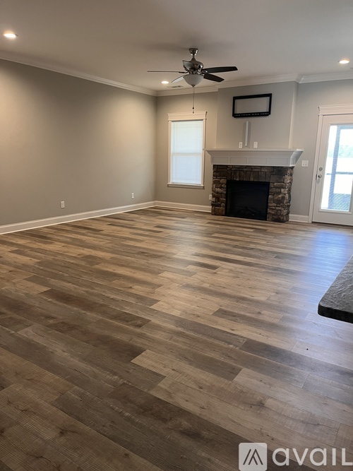 A spacious room with a fireplace and a fan on the ceiling.