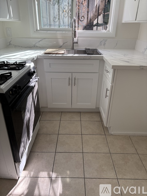 A kitchen with a black stove top oven and white cabinets.