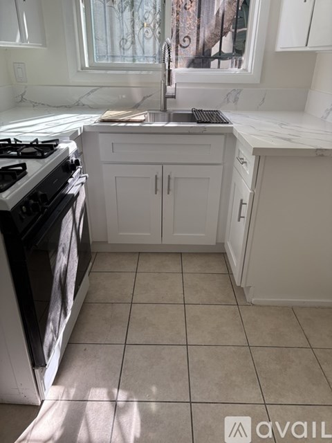 A kitchen with a black stove top oven and white cabinets.