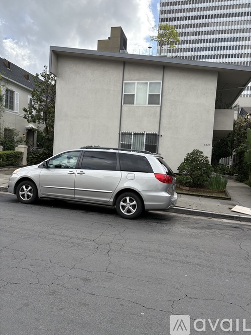 A silver car is parked on the side of a street.
