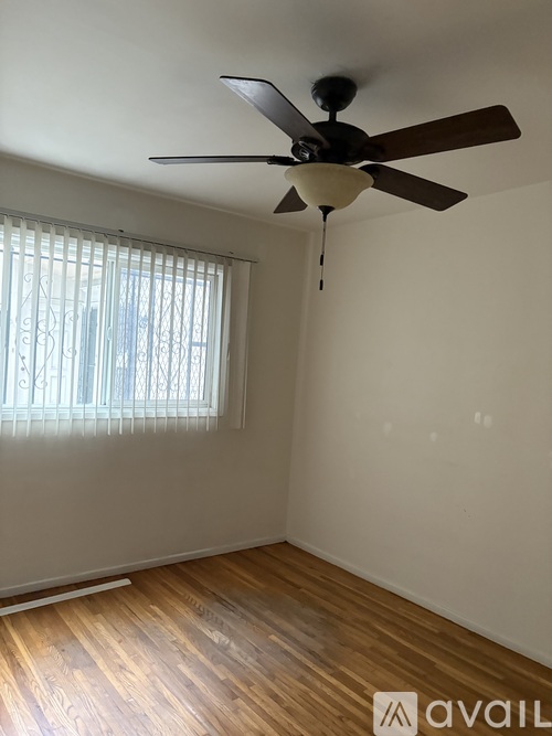 A room with a ceiling fan and a window with blinds.