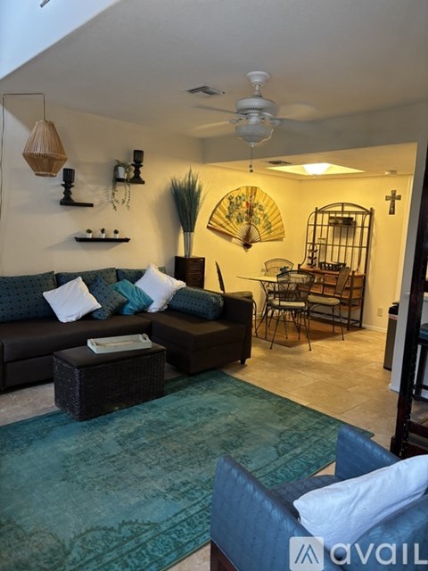A living room with a brown couch and a fan on the ceiling.