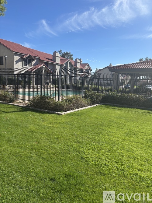 A well-maintained lawn in front of a gated community with a pool.