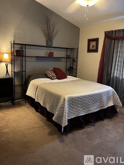 A bedroom with a bed, a bench, and a ceiling fan.