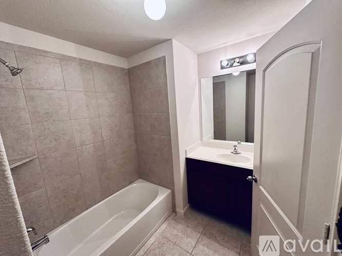 A bathroom with a tub, sink, and mirror.