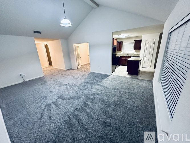 A spacious room with a carpeted floor and a ceiling fan.