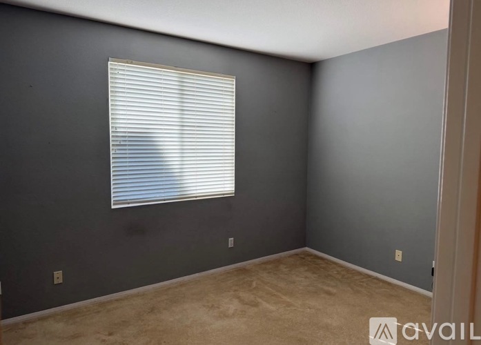 A room with a window covered by white blinds.