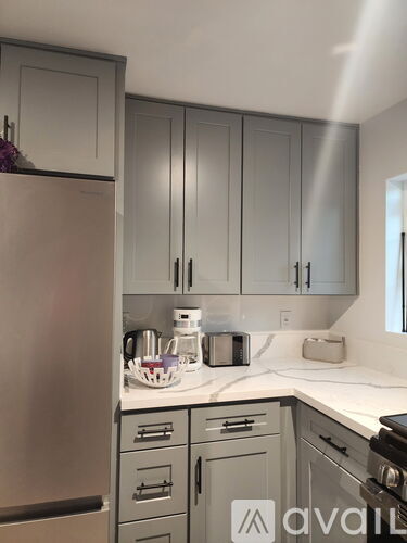 A kitchen with a refrigerator, cabinets, and a countertop with a toaster and a coffee maker.