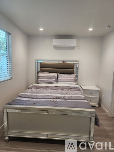 A bedroom with a bed, nightstand, and window with blinds.