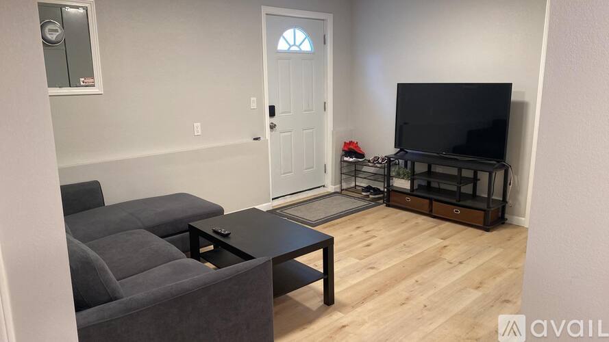 A living room with a grey couch, a black coffee table, and a television.