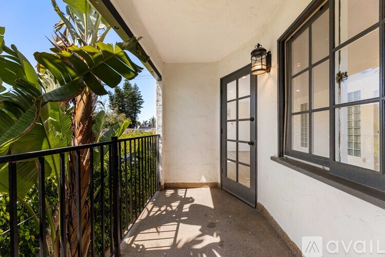 A balcony with a black railing and a wall with a window.
