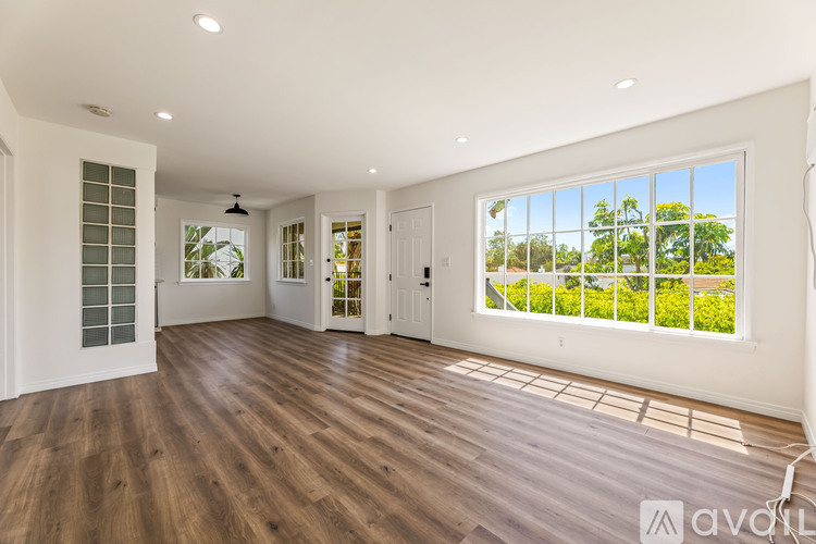 A spacious room with wooden floors and large windows.